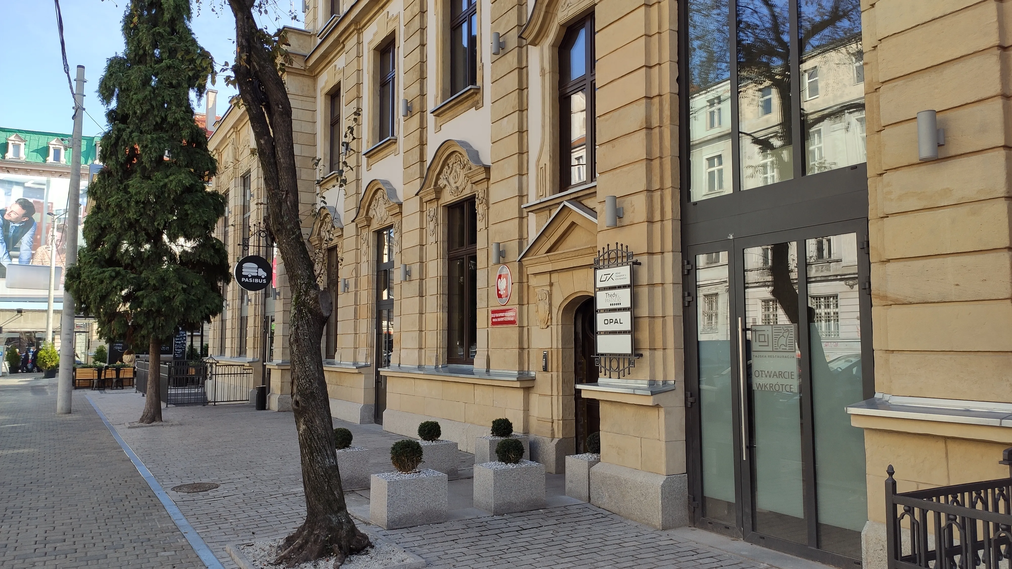 Stary Dworzec w Katowicach, budynek z żółtej płyty, stoi przy chodniku z szarek kostki brukowej.